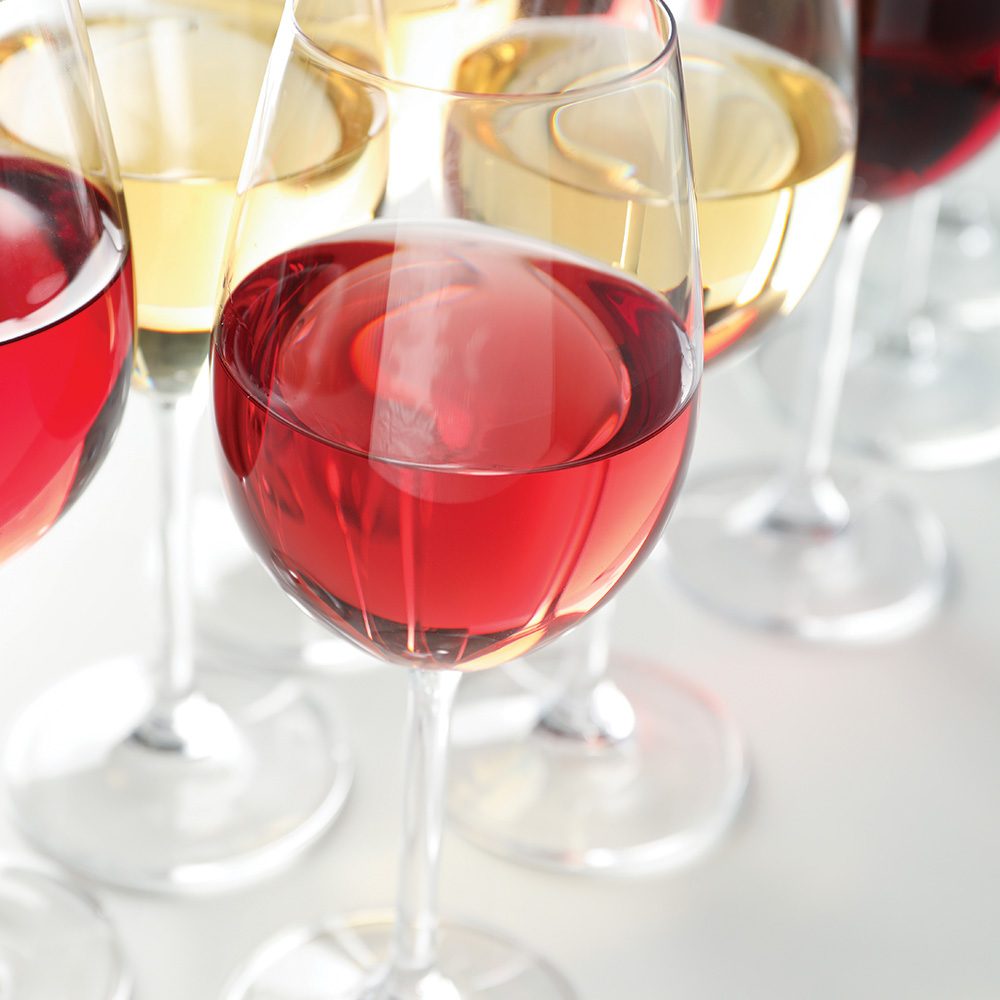 Glasses of white and red wine lined up on a table